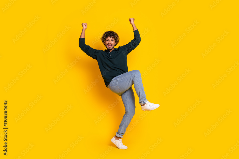 Energetic young man jumping with joy on yellow background celebrating success Energetic young man jumping with joy on yellow background celebrating success