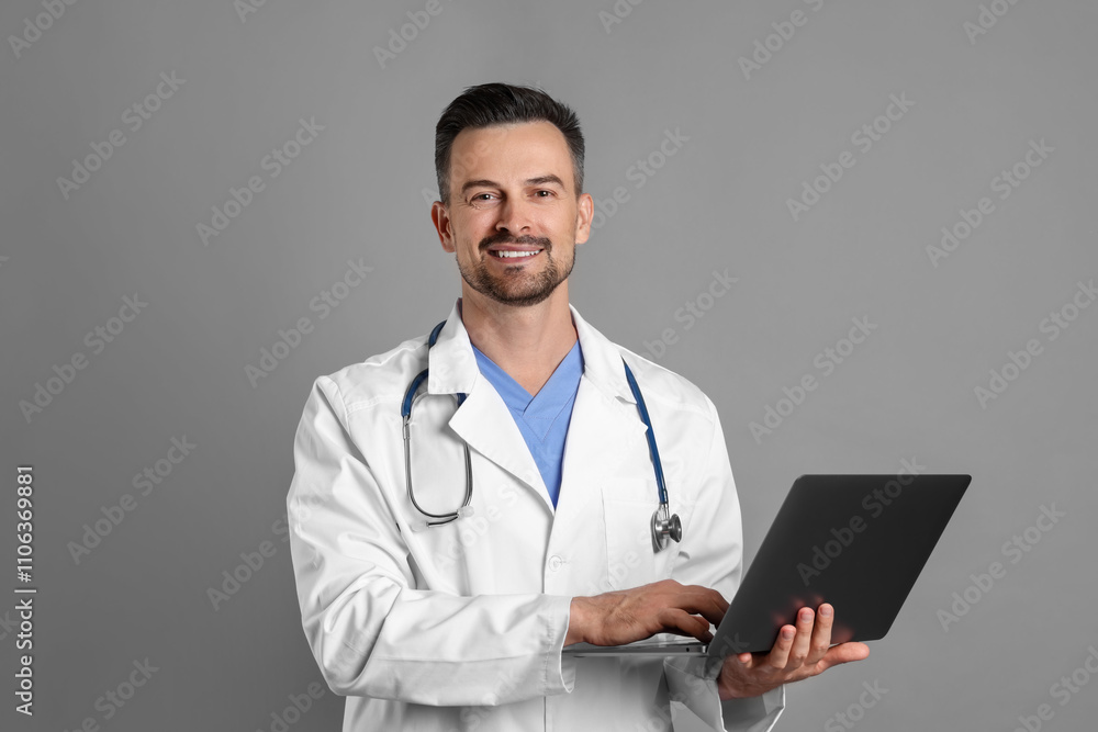 Smiling doctor with stethoscope and laptop on grey background Smiling doctor with stethoscope and laptop on grey background