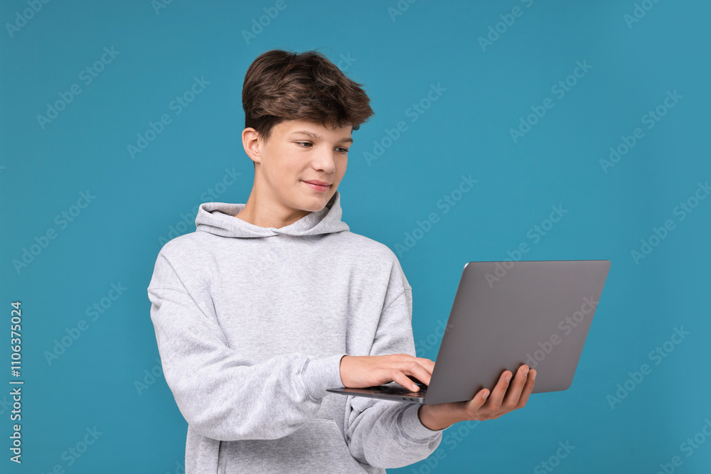 Teenage boy with laptop on light blue background Teenage boy with laptop on light blue background