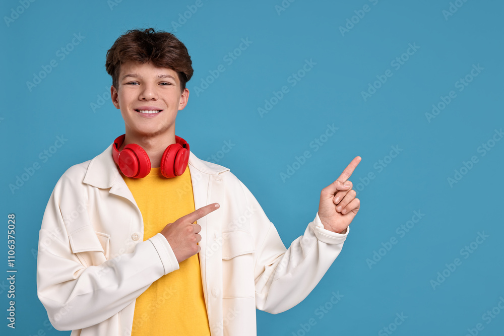 Happy teenage boy with headphones on light blue background, space for text Happy teenage boy with headphones on light blue background, space for text