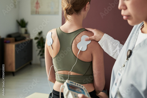 Fotografie Woman experiencing therapeutic session with electrodes on back monitored by prof