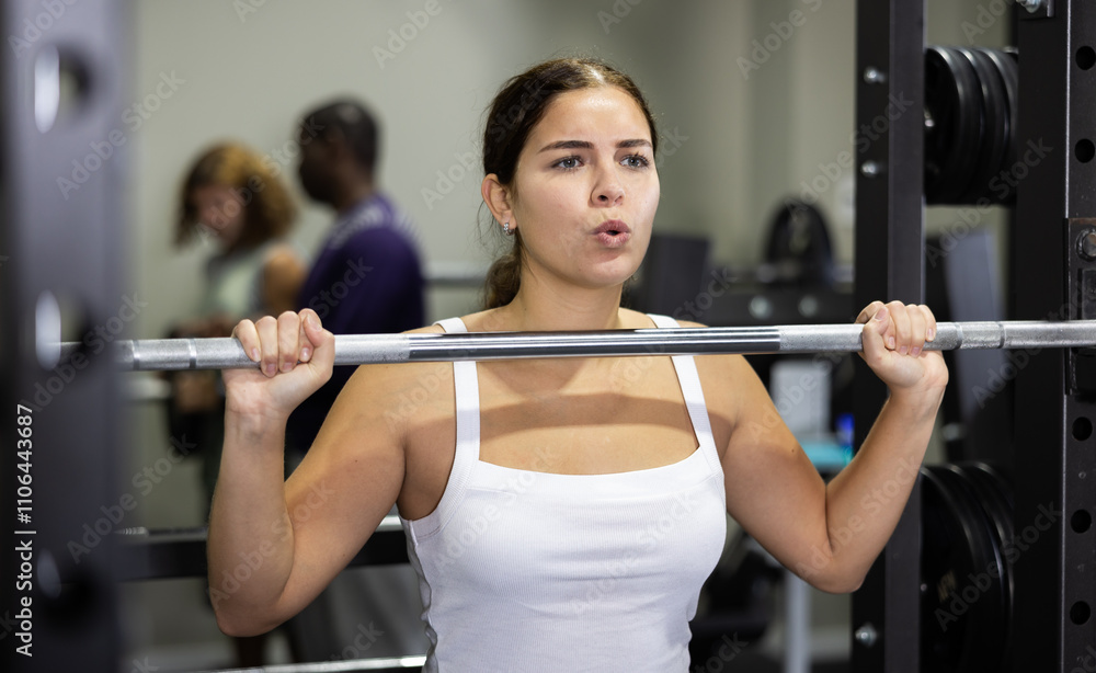 Caucasian woman training with barbell using squat rack in gym Caucasian woman training with barbell using squat rack in gym