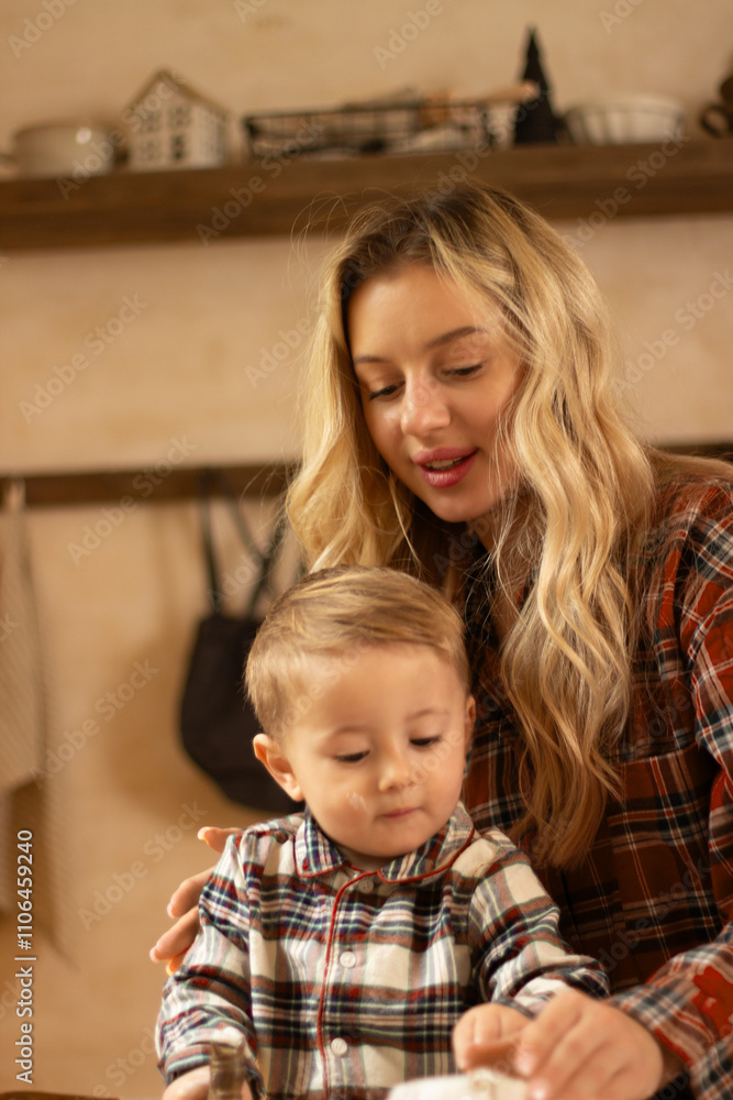 A mother with a one and a half year old child is preparing a festive dinner in the kitchen, dressed in checkered shirts, New Year's atmosphere A mother with a one and a half year old child is preparing a festive dinner in the kitchen, dressed in checkered shirts, New Year's atmosphere