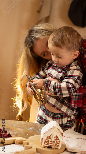 A mother with a one and a half year old child is preparing a festive dinner in the kitchen, dressed in checkered shirts, New Year's atmosphere photo