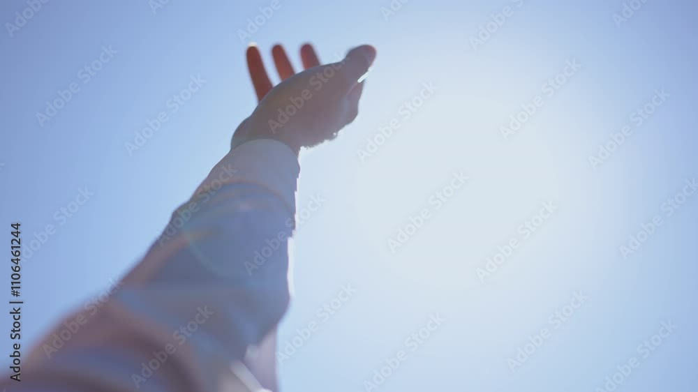 A hand is reaching upwards against a bright and clear blue sky, symbolizing hope, dreams, and aspirations in life A hand is reaching upwards against a bright and clear blue sky, symbolizing hope, dreams, and aspirations in life
