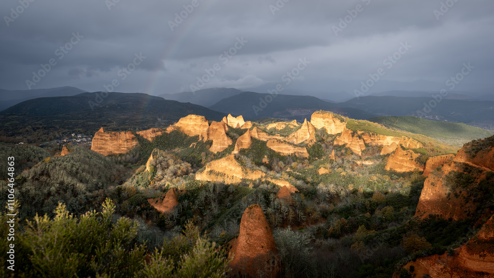 Fototapeta premium Las médulas ancient roman gold mines shining under cloudy sky and a rainbow at sunrise