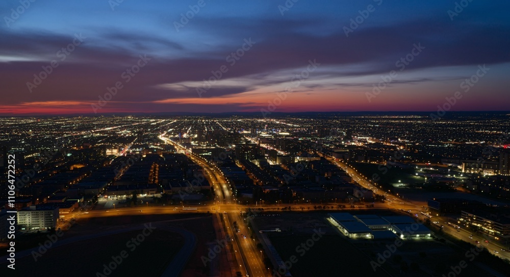 Fototapeta premium Aerial view of a cityscape with lights glowing at twilight