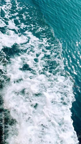 Close-up of a turbulent, foamy wake created by a boat motor, captured during a ride through clear, turquoise waters of Mediterranean Sea near Gibraltar. The scene highlights dynamic motion and energy