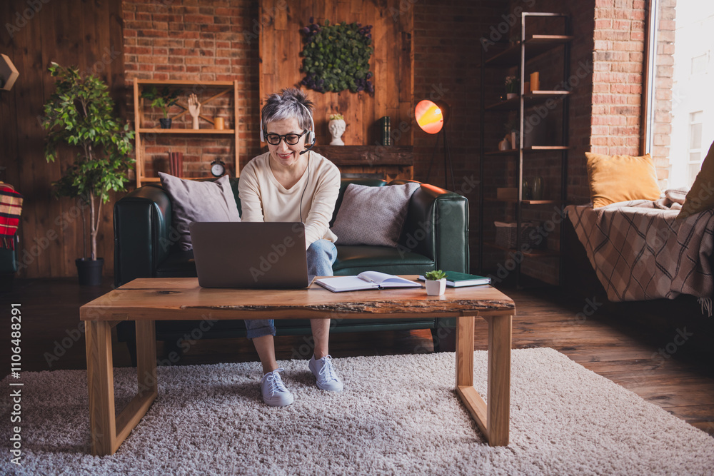 Mature woman with short grey hair enjoying leisure time indoors, using laptop at home. Comfortable and charming senior Mature woman with short grey hair enjoying leisure time indoors, using laptop at home. Comfortable and charming senior