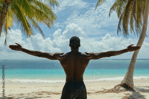 Man with outstretched arms embracing the serene tropical beach, surrounded by palm trees and a stunning ocean view under a vibrant sky filled with clouds. photo