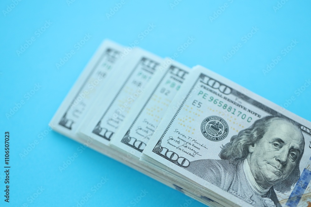 Big amount of hundred dollar bills in thick stack lies on bright blue color paper background Big amount of hundred dollar bills in thick stack lies on bright blue color paper background