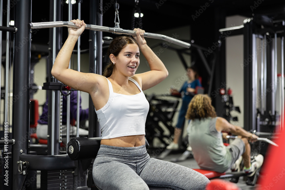 Caucasian woman training on lat pull down machine in gym Caucasian woman training on lat pull down machine in gym