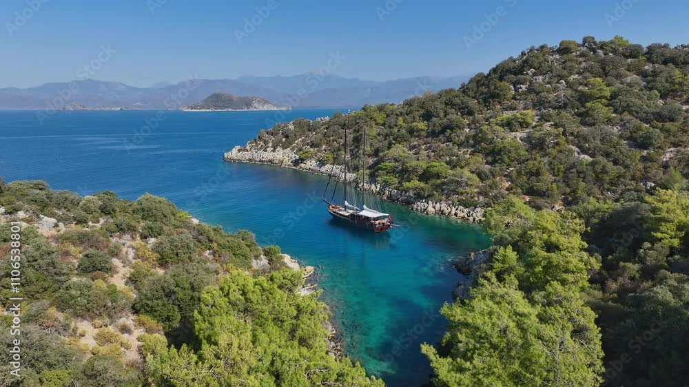 A gulet anchored near a beautiful coastline, surrounded by calm turquoise waters and lush green hills. A gulet anchored near a beautiful coastline, surrounded by calm turquoise waters and lush green hills.