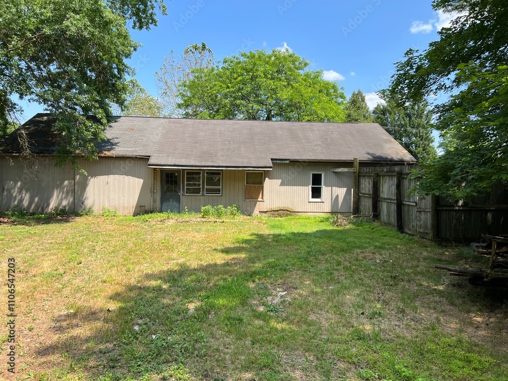 Very Old Wooden House with Weathered Exterior in a Fenced Backyard Surrounded by Overgrown Vegetation Very Old Wooden House with Weathered Exterior in a Fenced Backyard Surrounded by Overgrown Vegetation