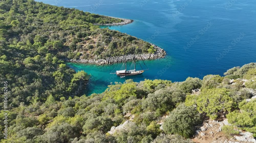 A gulet anchored near a beautiful coastline, surrounded by calm turquoise waters and lush green hills. A gulet anchored near a beautiful coastline, surrounded by calm turquoise waters and lush green hills.