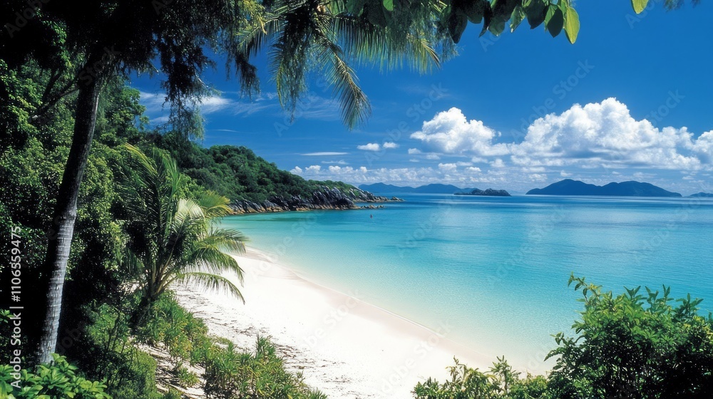 Idyllic tropical beach scene with white sand, turquoise water, lush green vegetation, and blue sky with fluffy clouds.