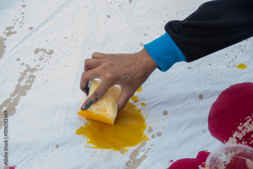 The process of coloring a piece of white cloth using a sponge. Students' creativity in making handicrafts using cloth as a medium at the Batik Ciprat Tulungagung Festival. photo