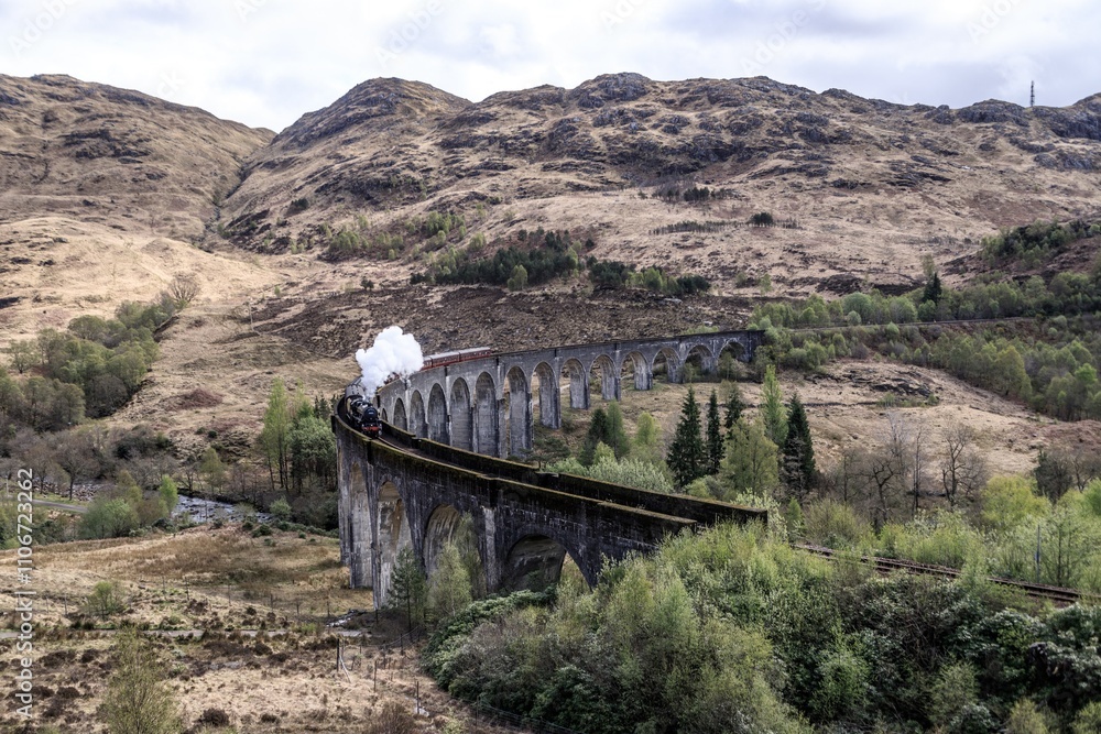 Fototapeta premium Majestic Steam Train Chugging Across the Glenfinnan Viaduct, Glencore, Scotland
