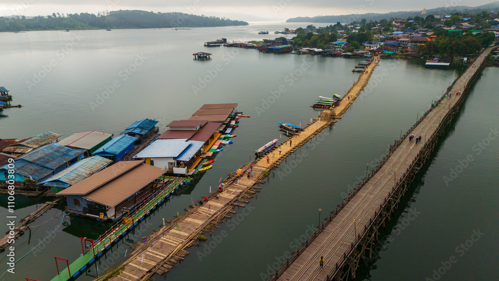drone fly above Mon bridge village in Sangkhlaburi Thailand covered in mist and fog with floating house aerial 