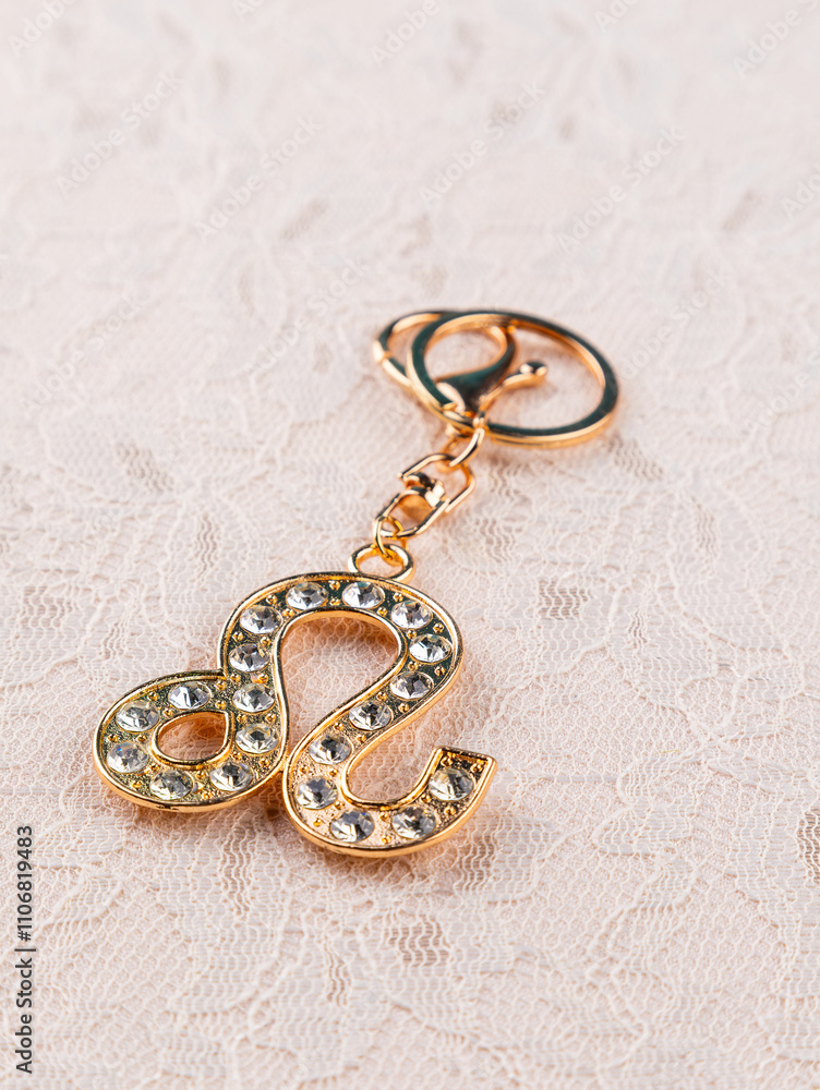 Close-up of golden keychain with rhinestones in the shape of the zodiac sign Leo on a light background Close-up of golden keychain with rhinestones in the shape of the zodiac sign Leo on a light background