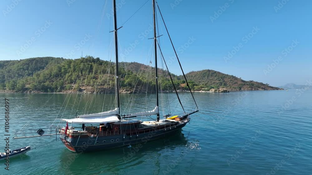 A gulet ship passing along a rocky coastline, with clear turquoise waters and rugged cliffs providing a dramatic and stunning backdrop. A gulet ship passing along a rocky coastline, with clear turquoise waters and rugged cliffs providing a dramatic and stunning backdrop.