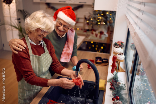 Fotografie Happy senior couple doing the dishes after making cookies for Christmas in the kitchen