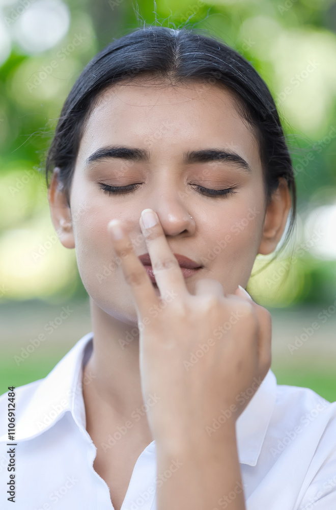 South Asian young woman practicing yoga breathing technique, surya bheda pranayama, the sun breathing with one nostril South Asian young woman practicing yoga breathing technique, surya bheda pranayama, the sun breathing with one nostril