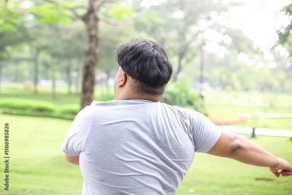 Back View Of Overweight Young Guy Warming Up His Body Before Jogging In The Park Back View Of Overweight Young Guy Warming Up His Body Before Jogging In The Park