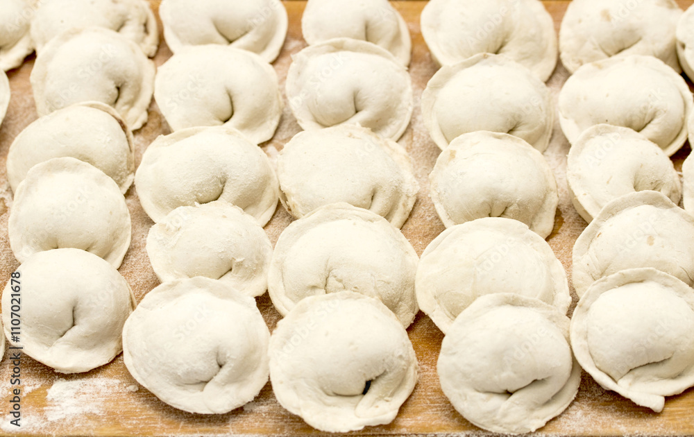 A large number of dumplings are sitting on a wooden table A large number of dumplings are sitting on a wooden table