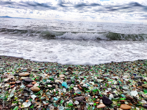 A beach with pebbles, glass and an incoming wave. Glass Bay in Vladivostok. Partial focus photo