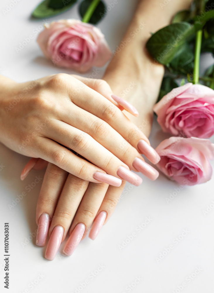 Fototapeta premium Woman showing her beautiful pastel pink manicure near pink roses