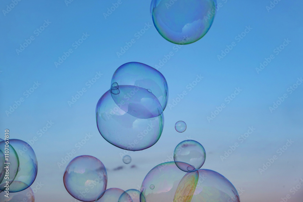 Magical soap bubbles floating in light blue sky with rainbow reflections Magical soap bubbles floating in light blue sky with rainbow reflections