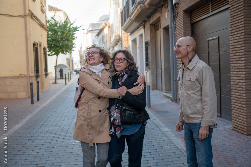 © C&A - Close-up of senior friends warmly embracing and chatting outdoors in a city neighborhood © C&A - Close-up of senior friends warmly embracing and chatting outdoors in a city neighborhood