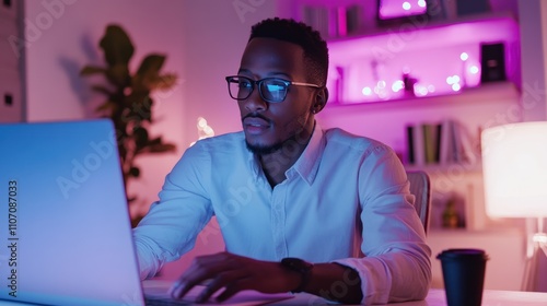 Man working on laptop at night in home office.