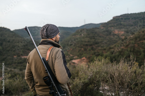 Hunter looking at the horizon with rifle on shoulder