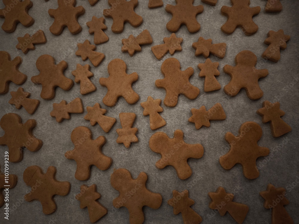 Gingerbread men and comets cookies baking on a tray and paper, ready for the holiday season christmas Gingerbread men and comets cookies baking on a tray and paper, ready for the holiday season christmas