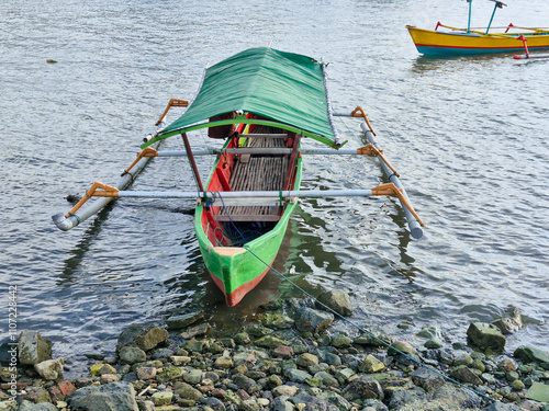 Green fishing boat is anchored at the beach photo