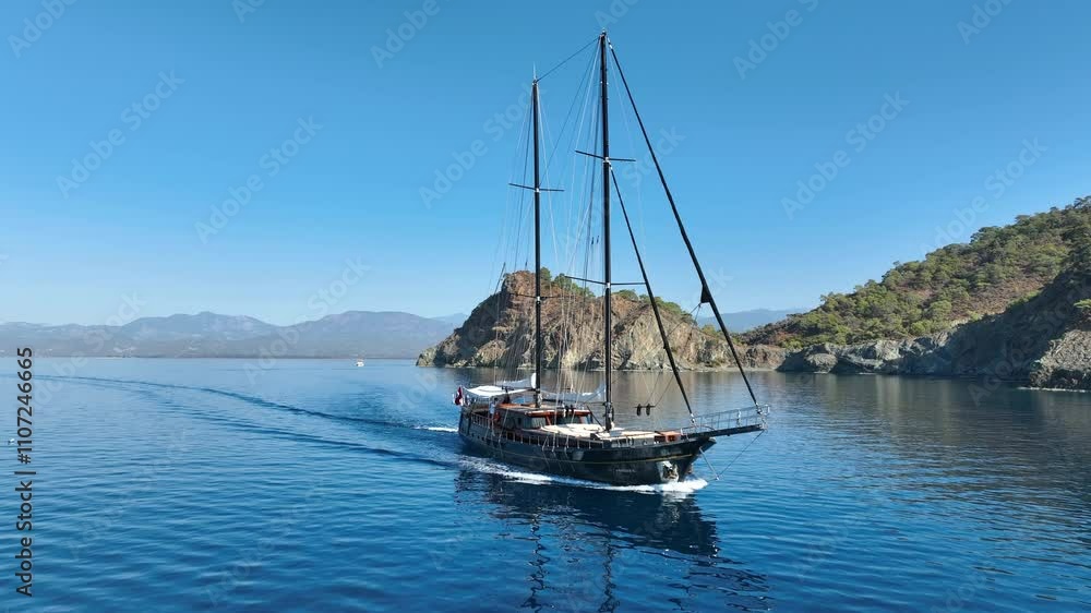 A gulet cruising smoothly on the open sea, with its sails catching the breeze and turquoise waters sparkling under the sun A gulet cruising smoothly on the open sea, with its sails catching the breeze and turquoise waters sparkling under the sun
