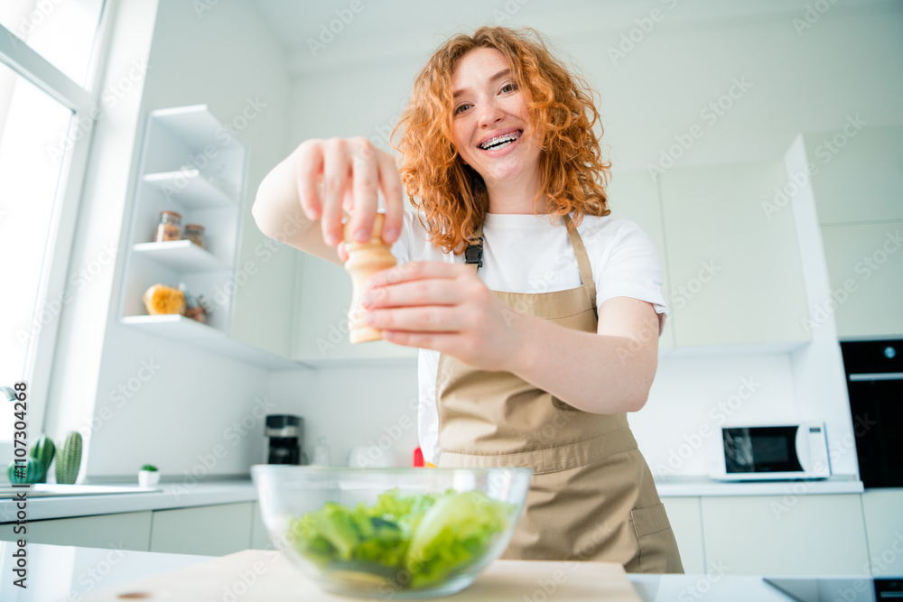 Young woman with red hair enjoys preparing a fresh salad in a bright and modern kitchen Young woman with red hair enjoys preparing a fresh salad in a bright and modern kitchen