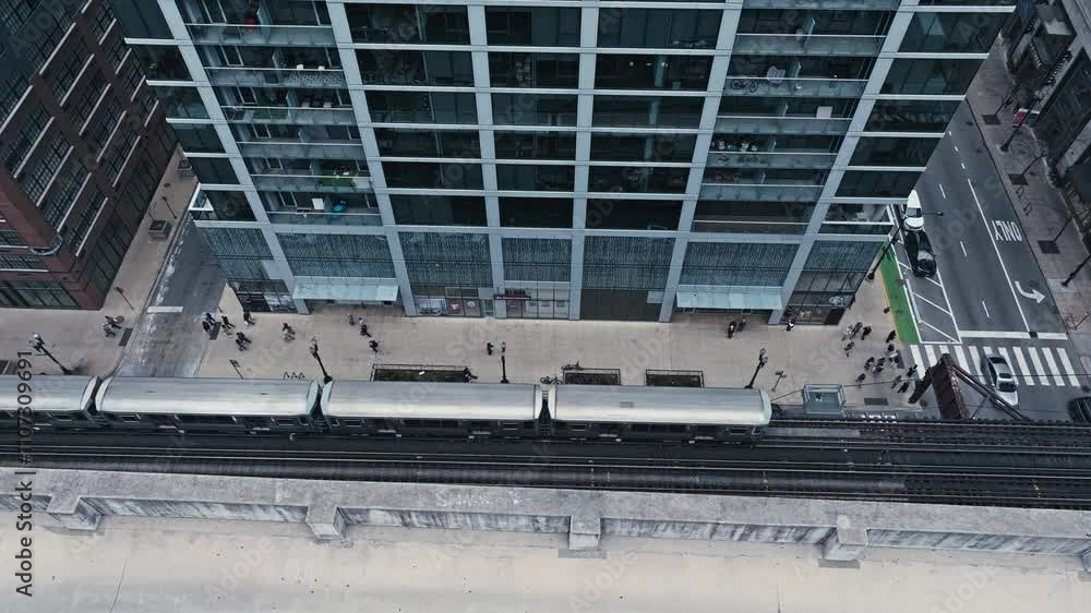 Aerial tracking tilt down of Chicago vibrant tram line with people walking surrounded by the urban skyline
