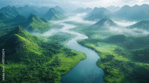 Aerial view of a lush green valley with a winding river amidst misty mountains.