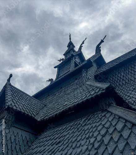 Low angle view of the wooden roof of the 12th century Norwegian Viking stave church of Borgund, with medieval craftsmanship bellow a cloudy sky photo