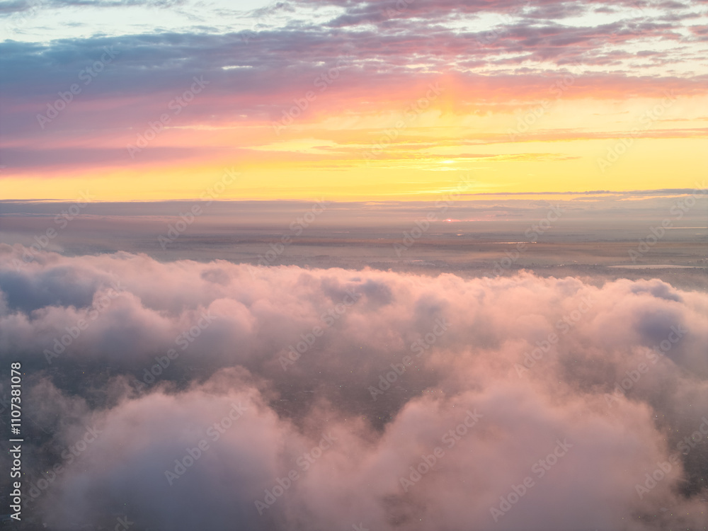Naklejka premium Drone view of clouds at sunset. Beautiful clouds covered the city. Bright evening golden, pink and blue landscape.