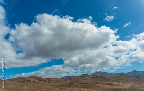 A panoramic view of Gran Tarajal town, Fuerteventura, Canary Islands, Spain. The photo showcases the colorful buildings lining the sandy beach, with gentle waves lapping at the shore under a clear blu