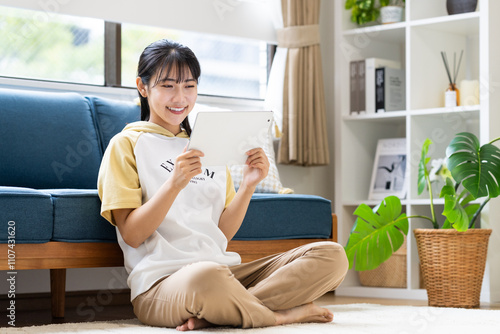 リビングでタブレットを使う若い女性 photo