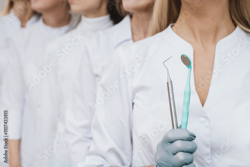 Team of dentists closeup hands in sterile disposable gloves with instruments. Dental modeling irons, tweezers, set of steel dental instrumentsб mirror held in hands group of dentists in white coats photo