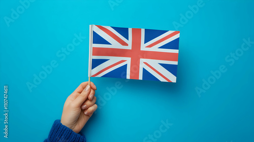 Hand Holding Union Jack Flag,  Patriotic Symbol on Blue Background,  Celebrating British Culture,  Illustrative Image photo