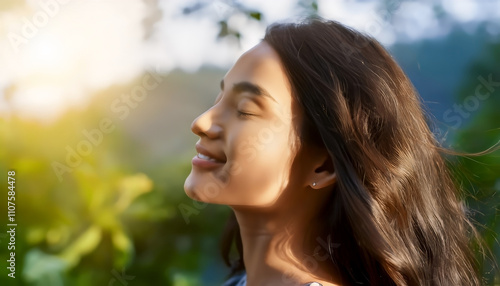 Young woman with long hair enjoying sun with closed eyes getting natural vitamin D outdoors photo