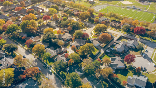 School district with football field in residential neighborhood suburban houses streets colorful fall foliage autumn leaves in Coppell, Dallas County, fast growing suburbs housing market, aerial photo