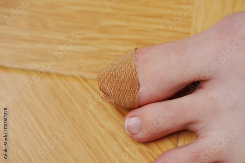 adhesive plaster on the big toe with nail injury. The background is a wooden surface. photo